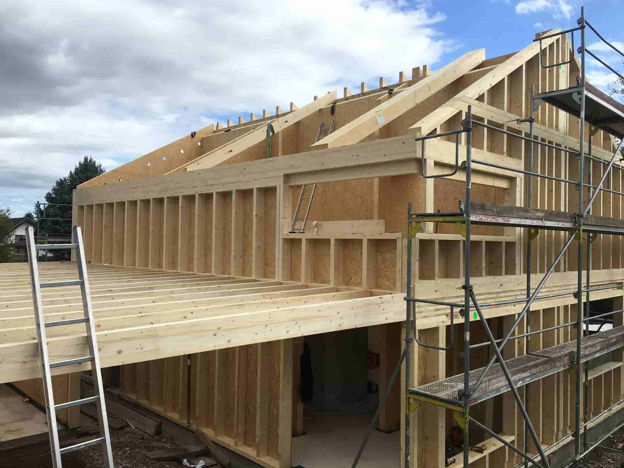 Holzrahmenbau mit Satteldach und Gerüst im Rohbau